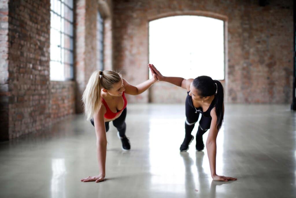 2 women highfiving while in a plank