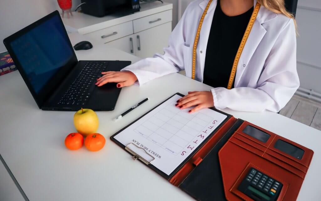 Picture of dietitian sitting at a desk with a laptop and some fruit