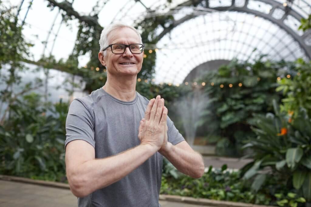 Older man in yoga pose smiling at the camera