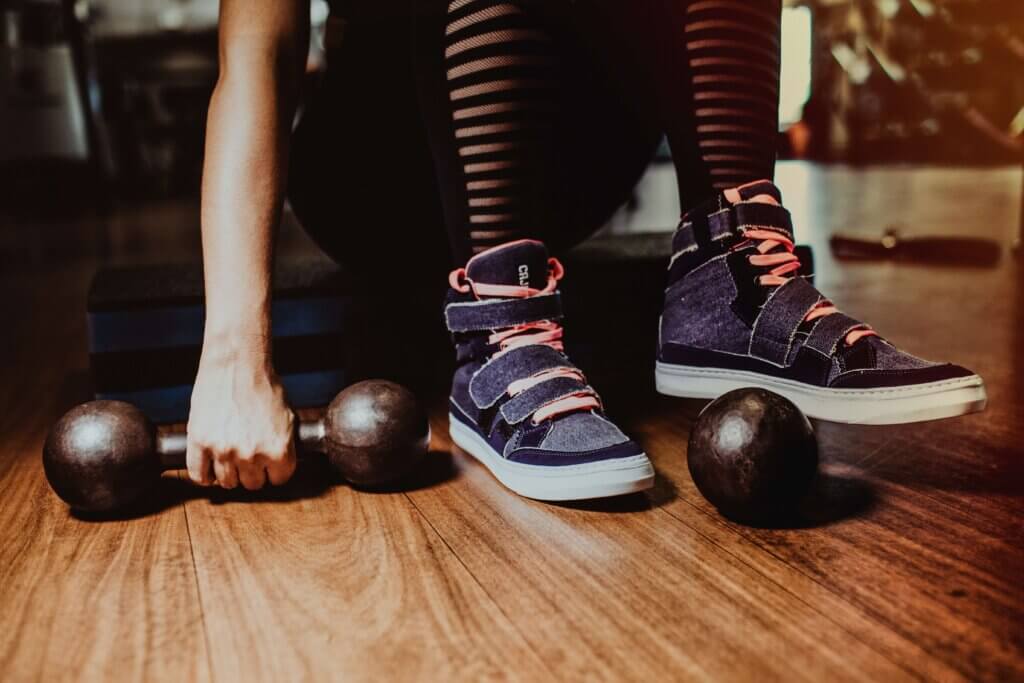 Woman sitting on a step with dumbbells on the ground next to her