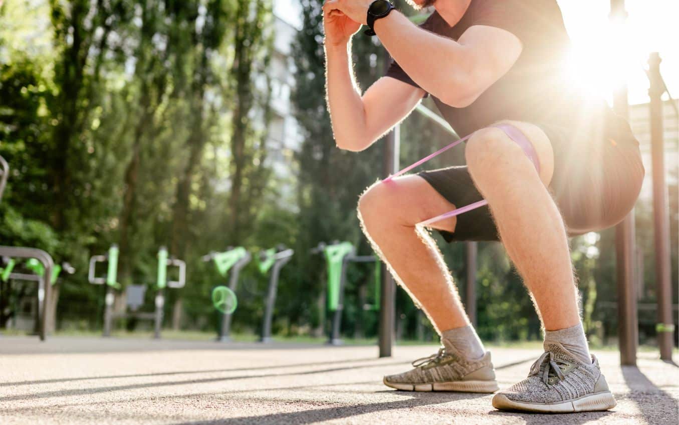 A picture of a man exercising outdoors at a park with workout equipment