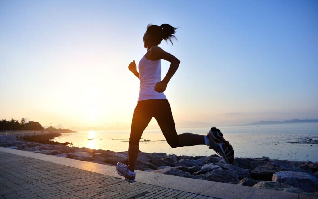 A picture of a woman running outside near a beach